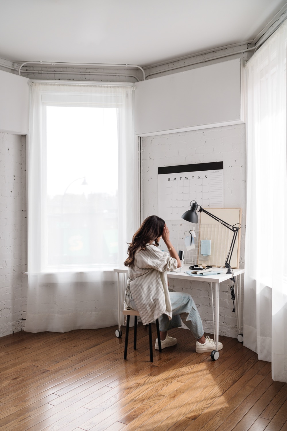 A woman working at a desk in a bright bay window